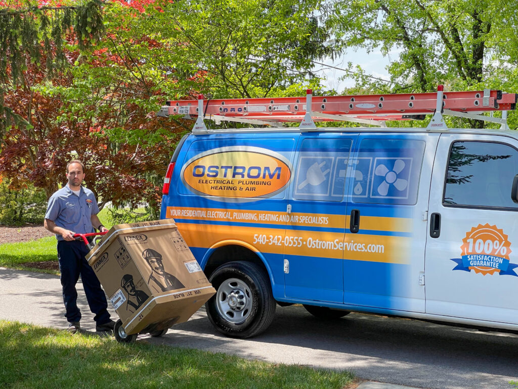 Ostrom HVAC technician with a new Lennox AC unit on a dolly, next to a service truck.