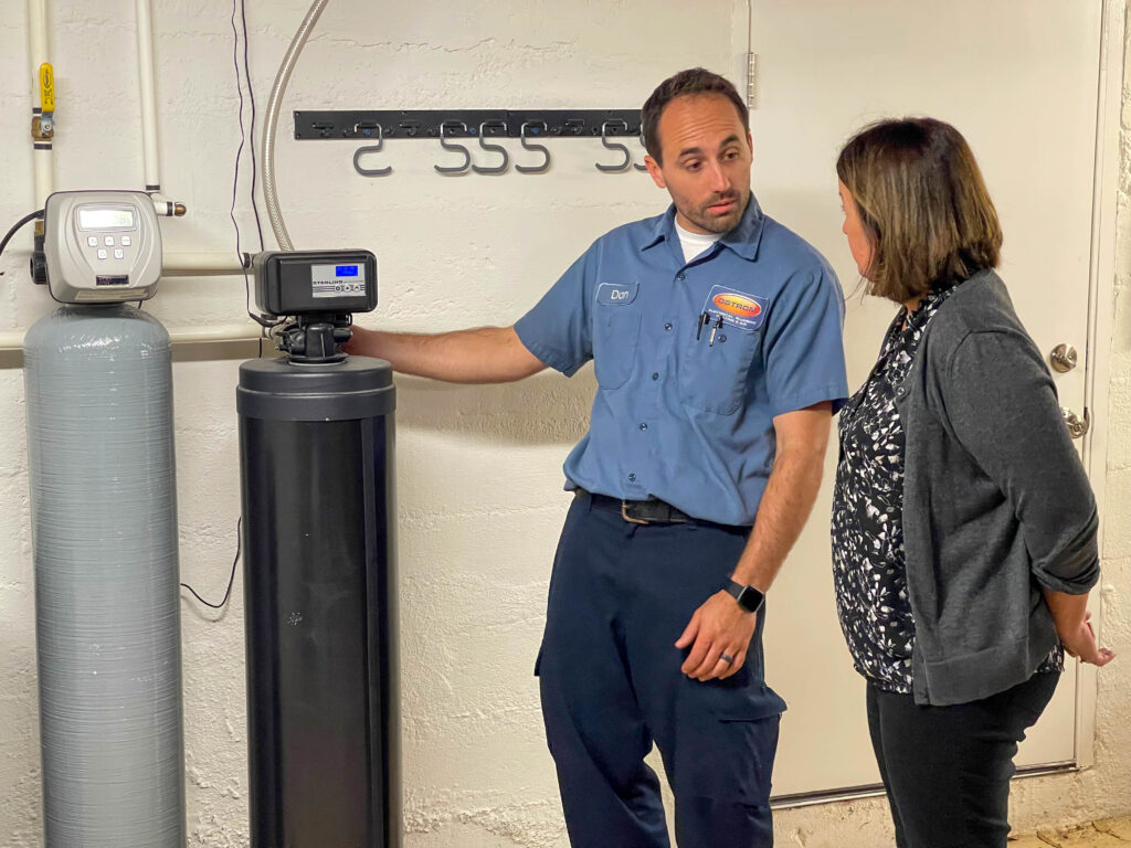 Ostrom plumber showing a homeowner their new water softening system