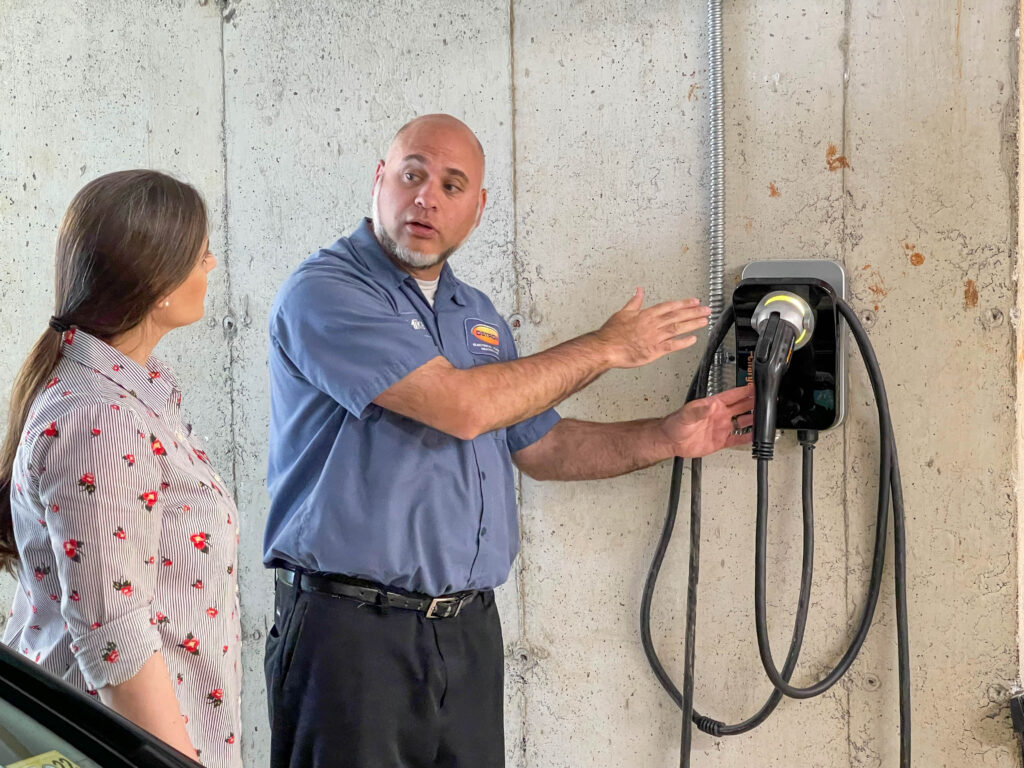 EV charger station installation. Ostrom technician explaining system to homeowner.