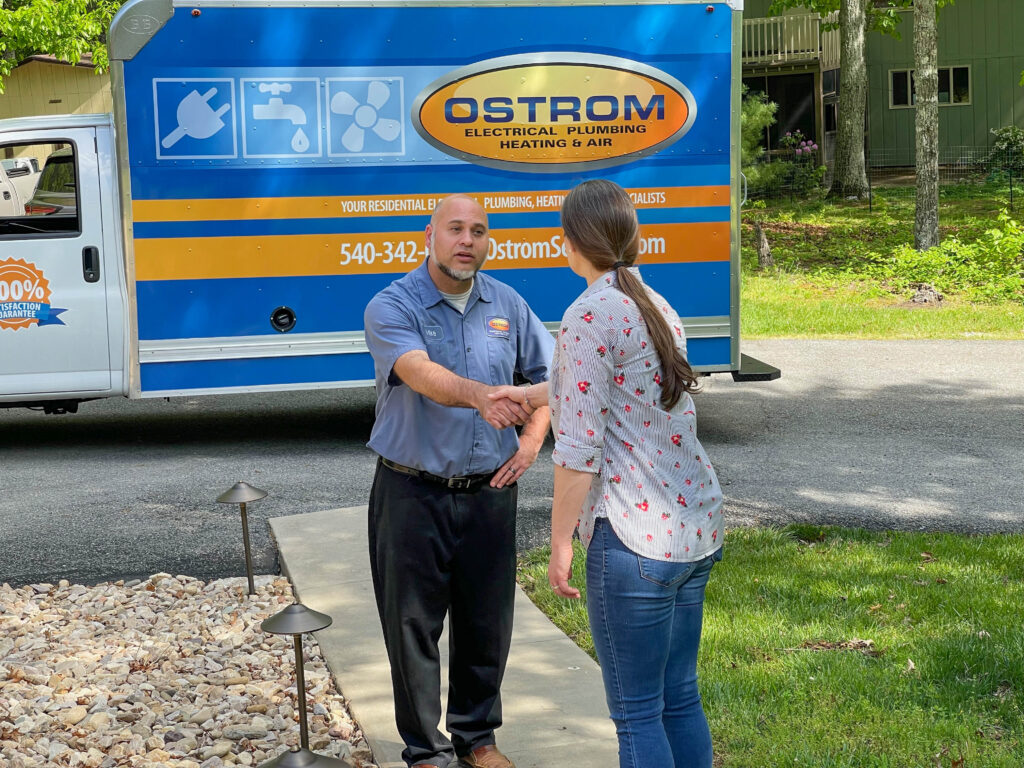 Ostrom electrician greeting a customer outside their home. Service truck in background.