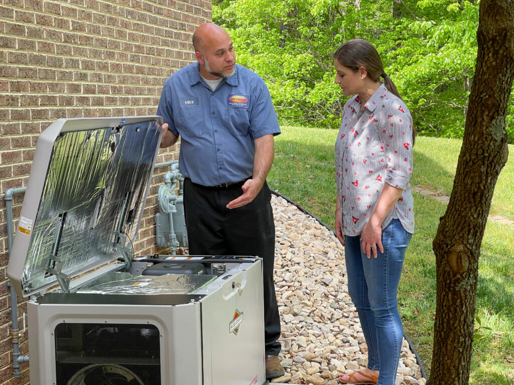 Ostrom electrician showing a homeowner their new generator outside brick home.