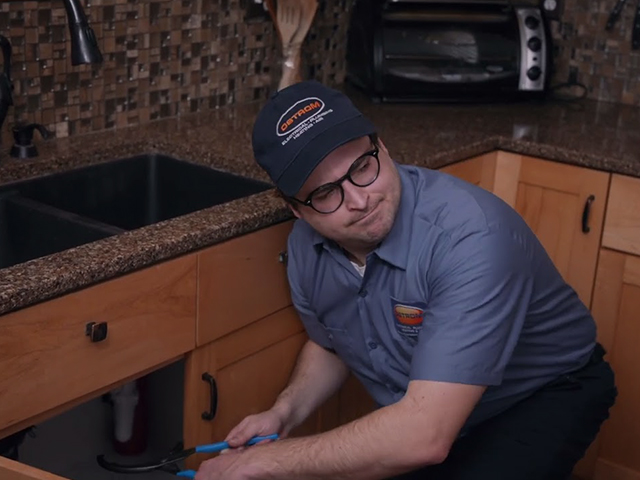 Ostrom plumber working under kitchen sink