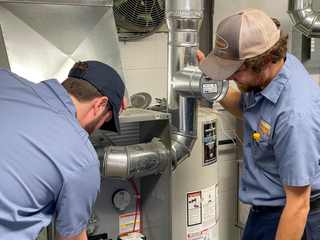 Two Ostrom technicians servicing a furnace