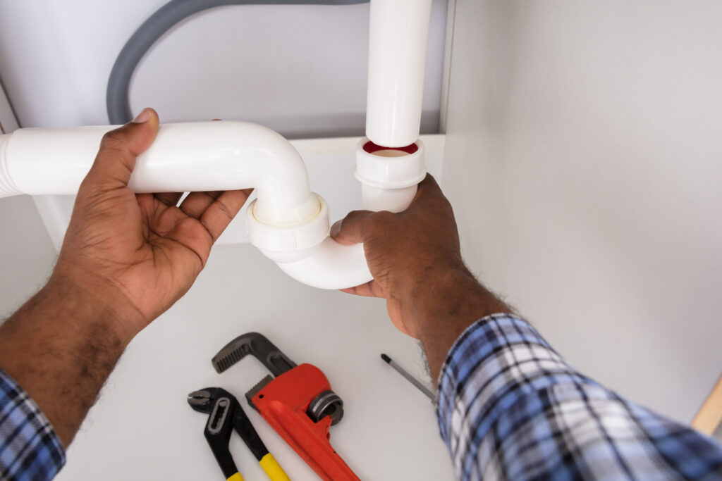 Close-up of plumber's hands fitting sink pipe in a bathroom.